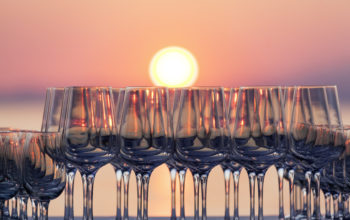 Wein Gläser in Reihe vor untergehender Sonne.