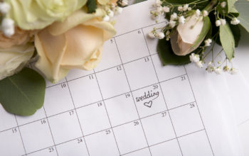 Choosing wedding date with pen writing heart on paper calendar on background